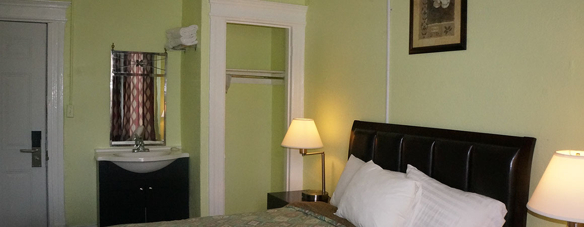 A hotel room with a bed, nightstand, and sink