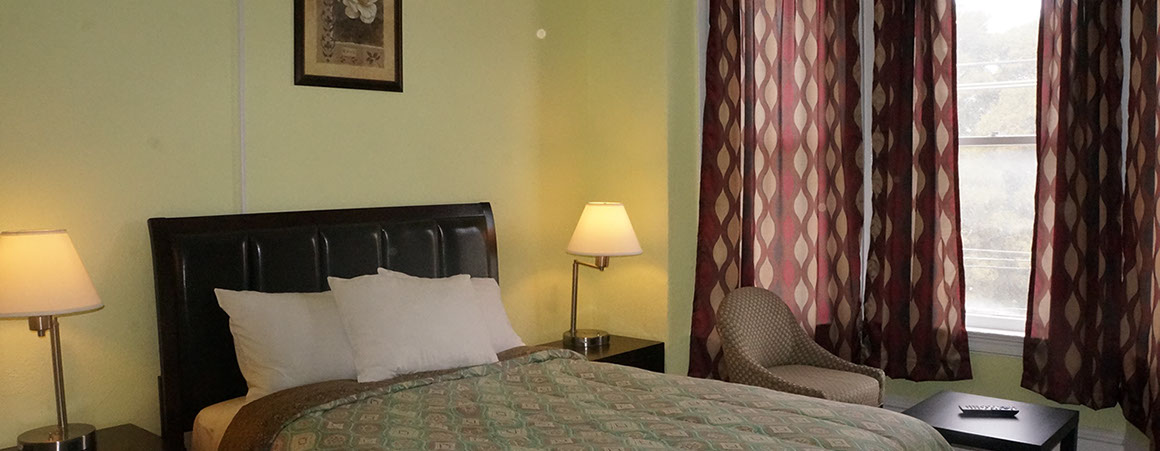 A hotel room with a bed, nightstands, lamps, a chair, and a window.